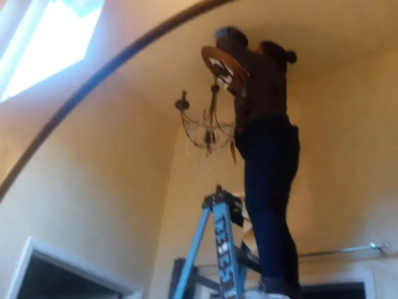 Electrician installing a chandelier in a Green Valley residence